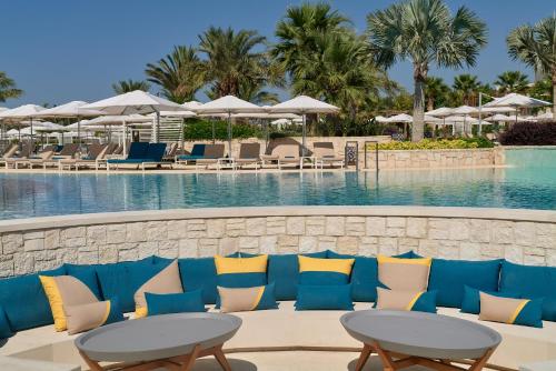 a pool with blue and yellow pillows and tables and chairs at City of Dreams Mediterranean - Integrated Resort, Casino & Entertainment in Limassol