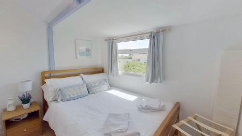 a bedroom with a white bed with a window at G23 Norda, Riviere Towans in Hayle