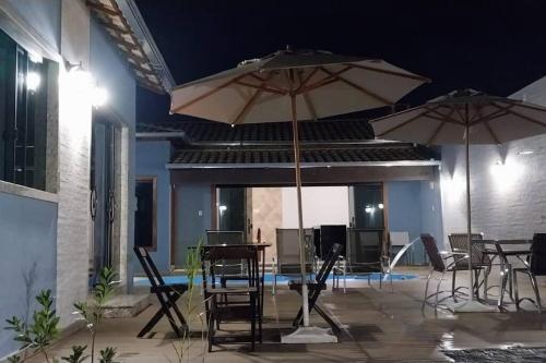 two tables and chairs with umbrellas on a patio at Espaço Dunei - Casa inteira com piscina in Catas Altas