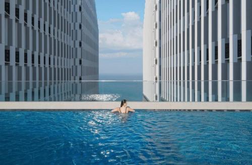a woman sitting in a swimming pool next to buildings at Apec Mandala Cham Bay Mui Ne 5* in Ấp Thiẹn Ái