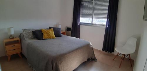 a bedroom with a bed and a chair and a window at Espacio C Montevideo con estacionamiento in Córdoba