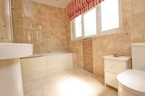 a bathroom with a tub and a toilet and a window at Beautiful character cottage in Saint Mawgan
