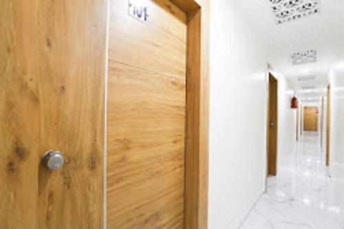 eine Holztür in einem Zimmer mit Fliesenboden in der Unterkunft Hotel Sunrise Inn in Ahmedabad