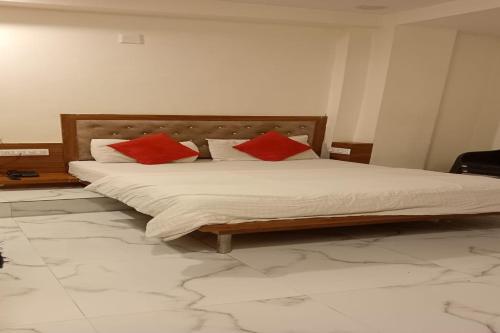 a bedroom with a bed with two red pillows at Hotel Sunrise Inn in Ahmedabad