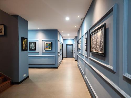 a hallway with blue walls and paintings on the walls at BKK Concept Hotel in Phnom Penh
