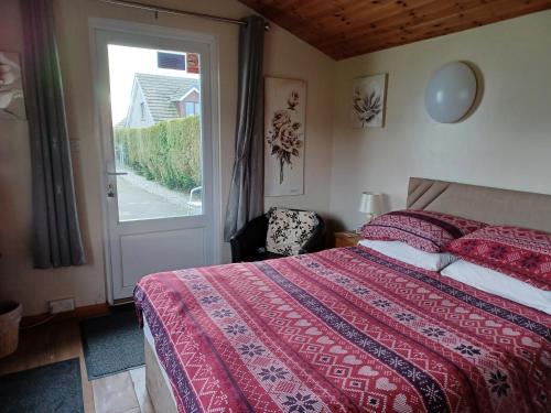 1 dormitorio con cama, ventana y puerta en Dunroaming Cabin, en Pendine