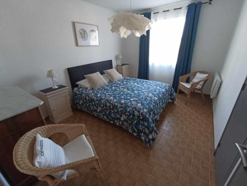 een slaapkamer met een bed met een blauwe deken en een raam bij Maison avec piscine in Villeneuve