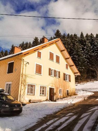 a yellow house with a car parked in front of it at Chalet Cosy Lisière de Forêt in Xonrupt-Longemer