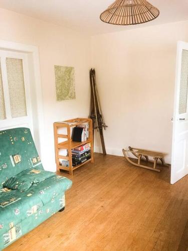 a living room with a green couch and a table at Chalet Cosy Lisière de Forêt in Xonrupt-Longemer