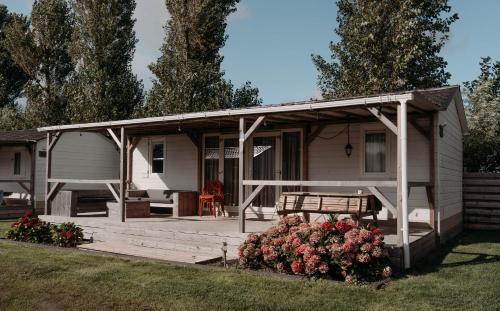 a small white house with a porch and a bench at Chalet Tulpenweide - recreatie in Breezand
