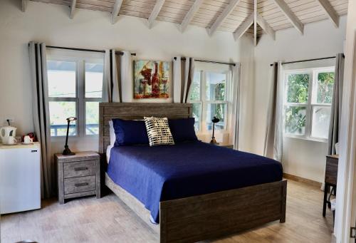 a bedroom with a bed with blue sheets and windows at The Moxy in English Harbour Town