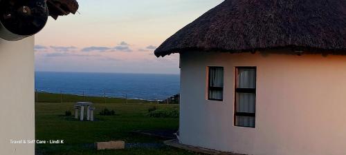 a building with a thatch roof and the ocean at Wild Coast Grosvenor Holiday Home in Lusikisiki