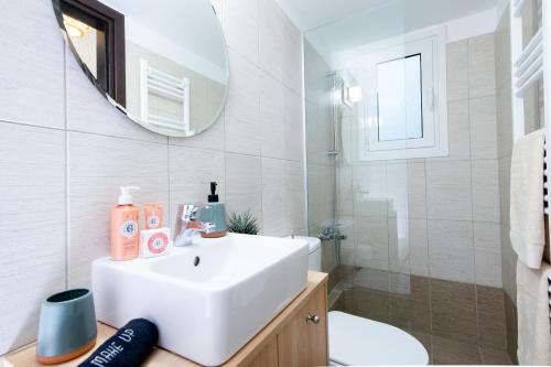 a white bathroom with a sink and a mirror at Piraeus Urban Gem in Piraeus