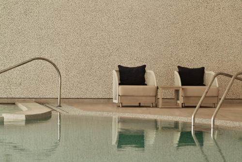 two chairs sitting next to a swimming pool at City of Dreams Mediterranean - Integrated Resort, Casino & Entertainment in Limassol