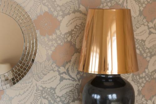 a black vase with a gold lamp next to a wall at Villa Rosa in Dunajská Streda