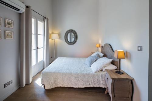 une chambre blanche avec un lit et une fenêtre dans l'établissement Garrigae Distillerie de Pezenas - Hotellerie & Spa, à Pézenas
