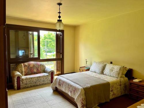 本图贡萨尔维斯Casa da Nona - Vale dos Vinhedos的一间卧室，里面有一张床、一把椅子和一扇窗户