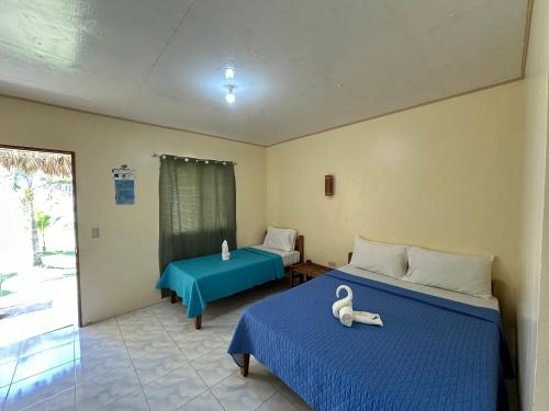 a room with two beds with blue sheets and a window at Dancalan Beach Resort in Donsol