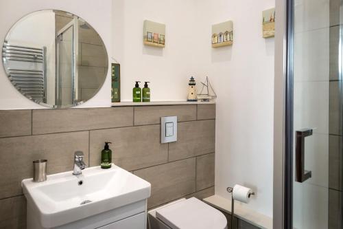 a bathroom with a sink and a mirror and a toilet at Gresham House in Eastbourne