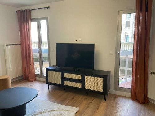 un salon avec une télévision à écran plat et une table dans l'établissement Le Botanique - À deux pas de Paris - 319B, à Rueil-Malmaison