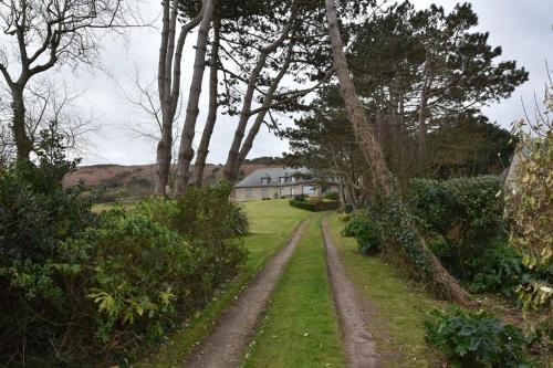 a dirt road in front of a house with trees at Les Tamaris 4 étoiles in Omonville-la-Rogue