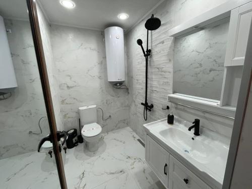 a white bathroom with a toilet and a sink at CHALET ELEVEN in Dospat