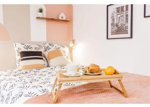 - une table basse avec un plateau de nourriture sur le lit dans l'établissement Charmant studio lumineux calme, à Asnières-sur-Seine