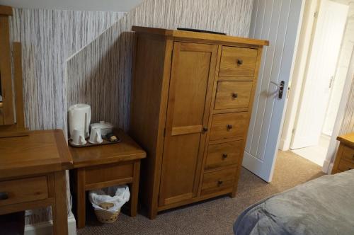 a bedroom with a wooden dresser and a desk with a dresservelt at Myrtle Bank Hotel in Gairloch