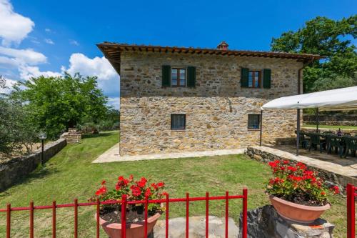 a stone house with a red fence and flowers at Villa Quercina in Pieve a Presciano