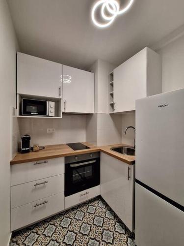 une cuisine avec des armoires blanches, un évier et un réfrigérateur dans l'établissement Le Traditionnel - En bordure de Paris - 322B, à Rueil-Malmaison