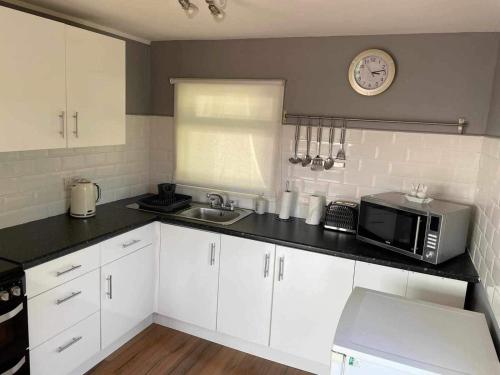 a kitchen with a microwave and a sink at 180 River View Cabin in Caeathro