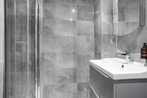 a bathroom with a shower and a sink and a mirror at BeiRoom Hyde Park Apartments in London