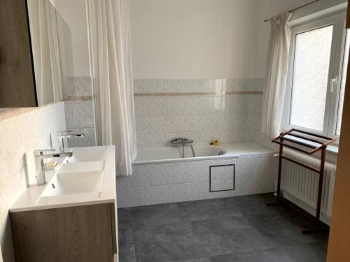La salle de bains blanche est pourvue d'une baignoire et d'un lavabo. dans l'établissement Une belle étage à Stockel, à Bruxelles
