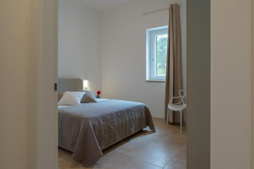 a white bedroom with a bed and a window at Villa Incanto con terrazza e piscina by Wonderful Italy in Ostuni