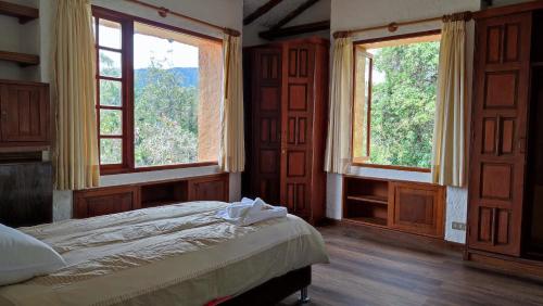 1 dormitorio con 2 ventanas y 1 cama. en Hacienda Raíces, en Subachoque