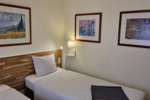 アルマダにあるMargarida Guest Houseのベッド2台付きの部屋、壁に2枚の写真が飾られています。