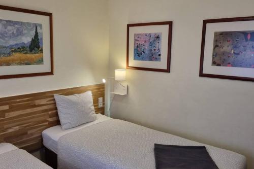 una camera con due letti e due quadri appesi al muro di Margarida Guest House ad Almada