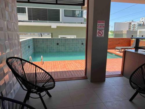 a patio with two chairs and a swimming pool at Praia de Palmas, Residencial Anito Petry! in Governador Celso Ramos