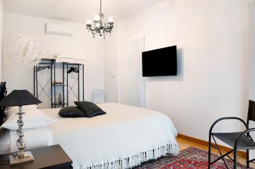 a white bedroom with a bed and a tv on the wall at Casa Gallinotto in Alba