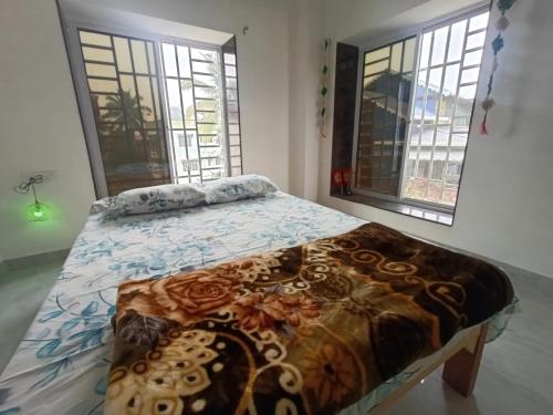 a bed in a room with two windows at Traveller's Nest in Siliguri