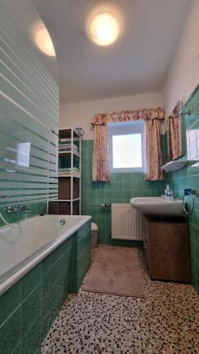 a green bathroom with a tub and a sink at Ferienwohnungen Mühlbacher in Sankt Martin