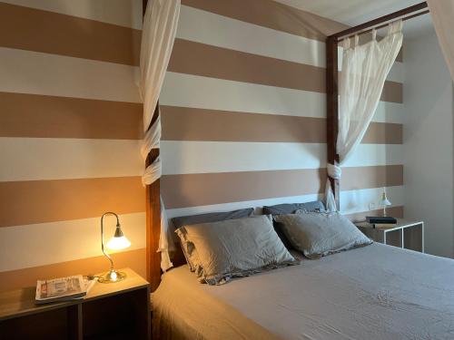 ein Schlafzimmer mit einer gestreiften Wand mit einem Bett und einer Lampe in der Unterkunft Villetta Rovizza in San Martino della Battaglia