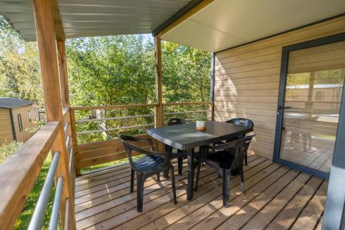 a screened porch with a table and chairs on it at Flower Camping La Sténiole in Granges-sur-Vologne
