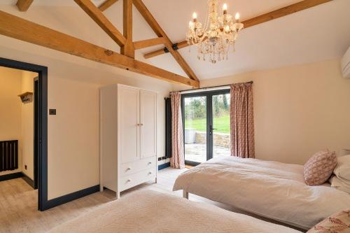 a bedroom with a bed and a chandelier at Finest Retreats - The Stables at Lilac Cottage in Hawling