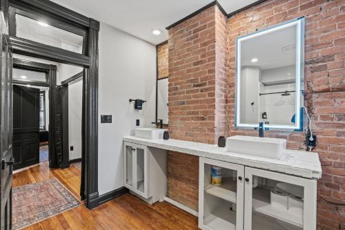 a bathroom with two sinks and a brick wall at Spacious, Historic Logan Circle Rowhouse in Washington