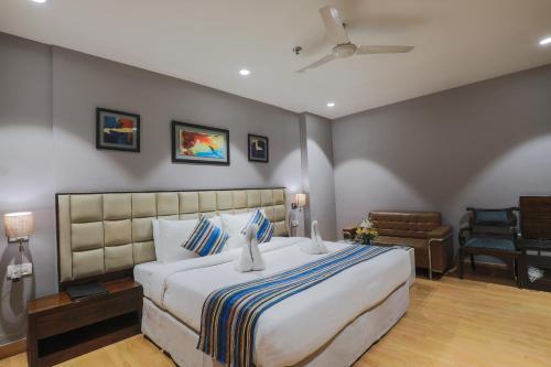 a bedroom with a large bed and a chair at Hotel Bluestone Nehru Place by The Cosy Hotels in New Delhi