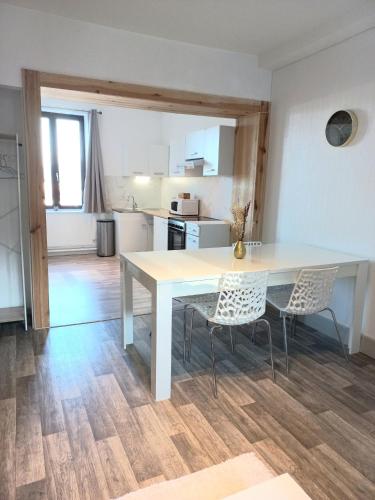 une table blanche et des chaises dans une cuisine dans l'établissement Appartement Les Iris, au calme, proche du centre, à Remiremont