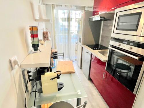 une petite cuisine avec des placards rouges et un four micro-ondes dans l'établissement Branly 2, by Welcome to Cannes, à Cannes
