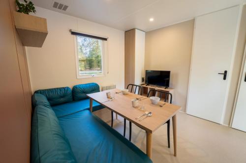 a living room with a blue couch and a table at Flower Camping La Sténiole in Granges-sur-Vologne