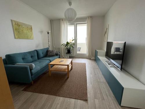 uma sala de estar com um sofá azul e uma televisão em Gemütlichkeit mit Cityblick em Leipzig